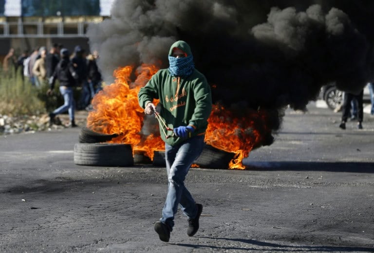 A masked Palestinian protester runs during clashes with Israeli troops in the West Bank city of Ramallah.