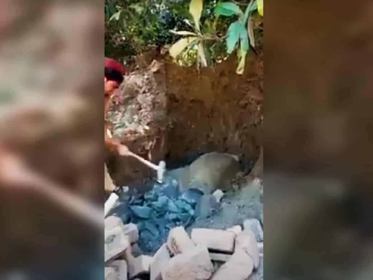 Man vandalising Buddha statue with a hammer.