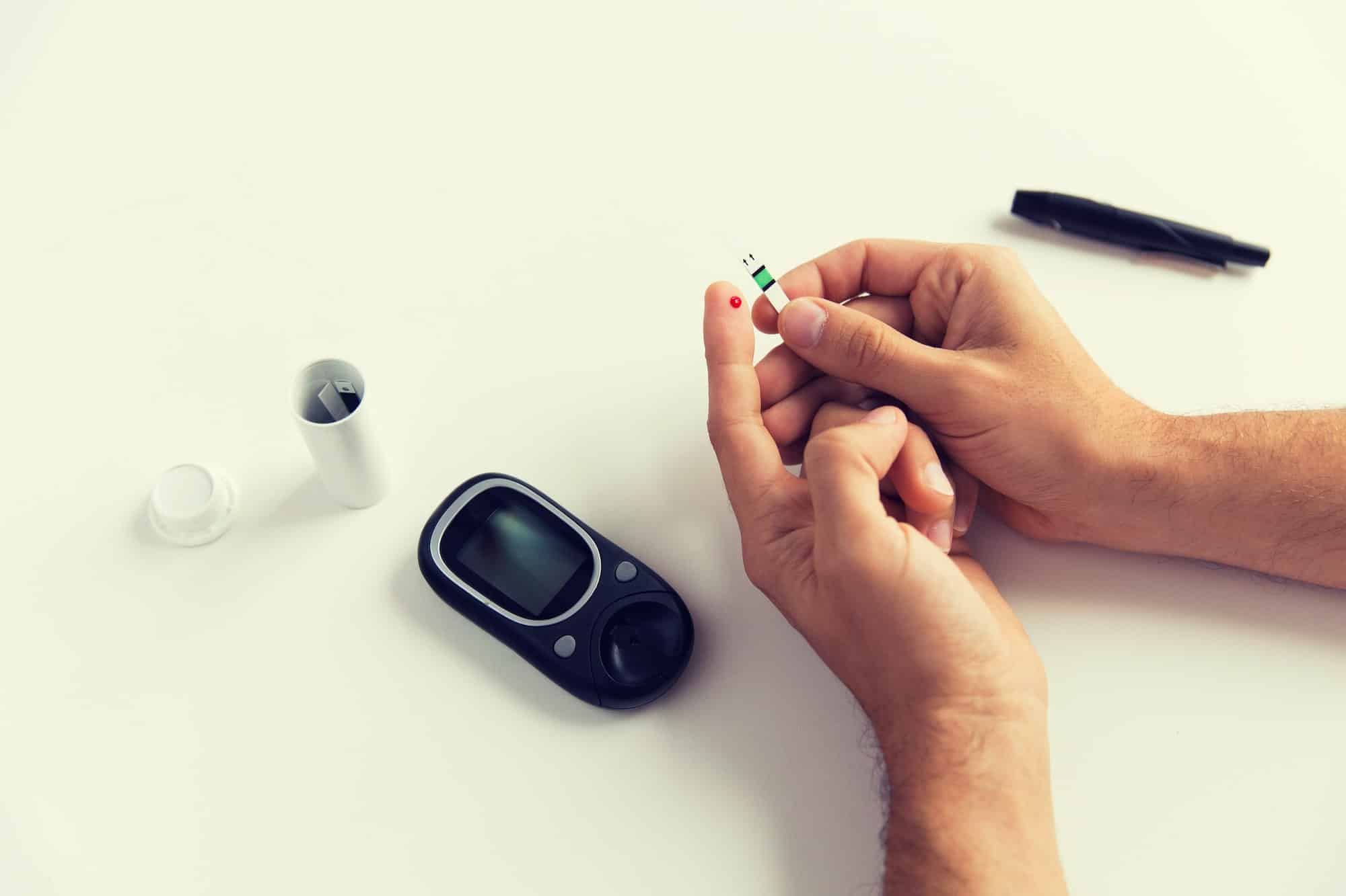 close up of man checking blood sugar by glucometer