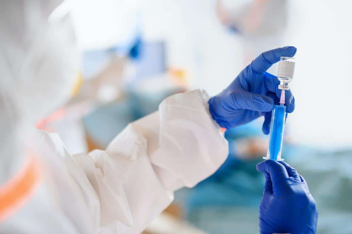 Unrecognizable doctor with vaccine in hospital, coronavirus concept