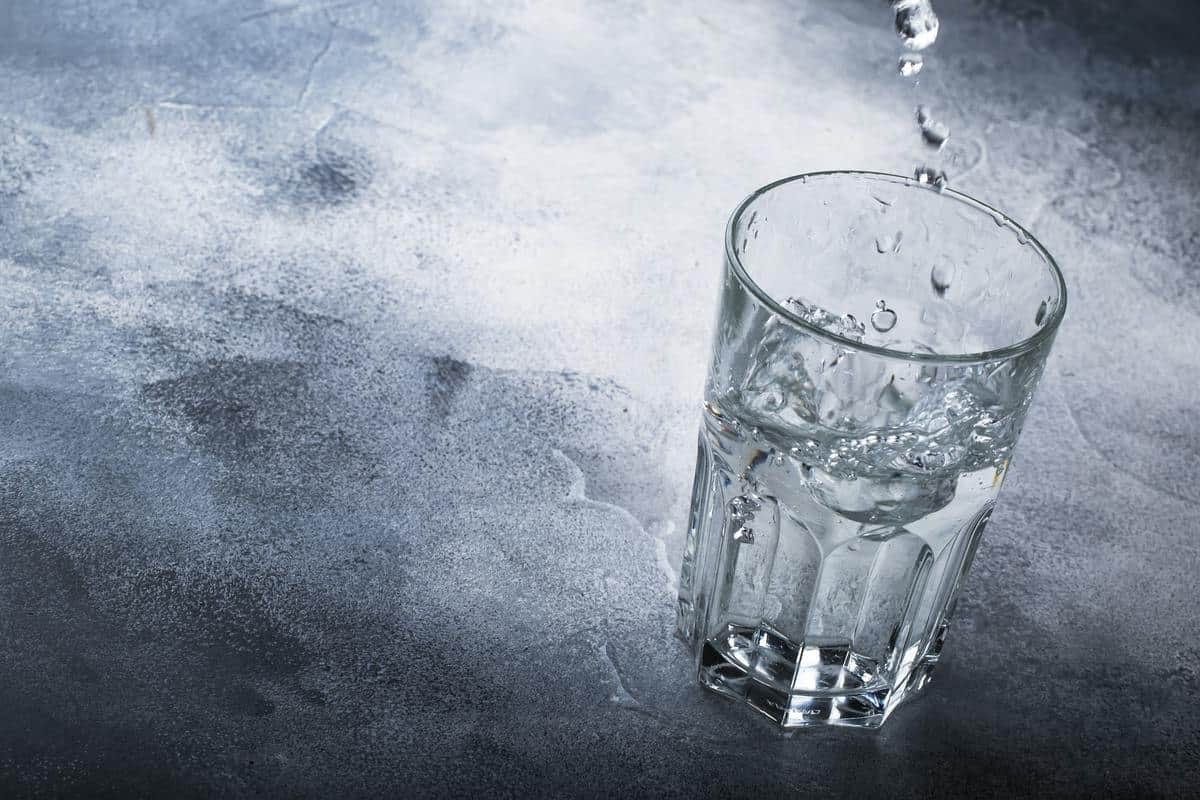 Last drops of pure water are poured into large glass cup