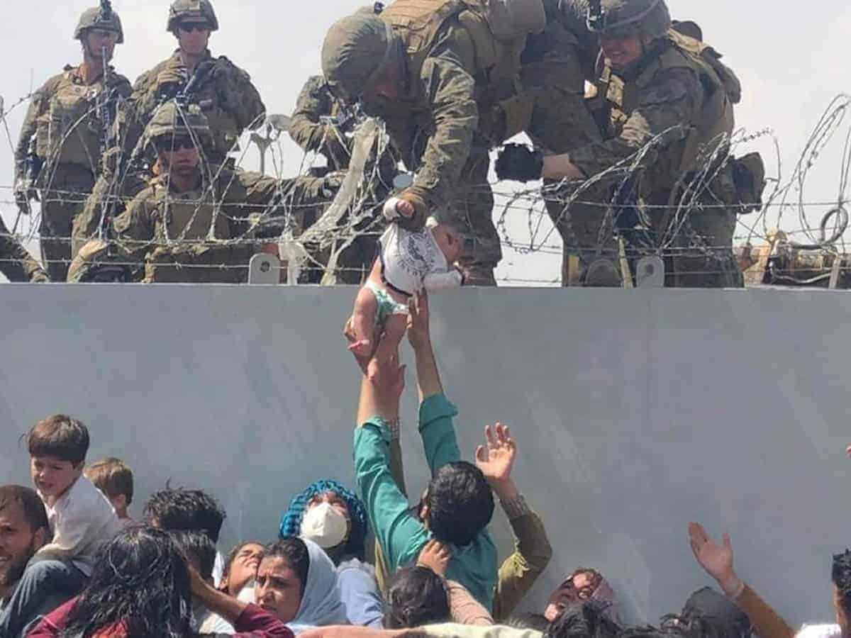 Baby passed over a wall at Kabul airport reunited with family